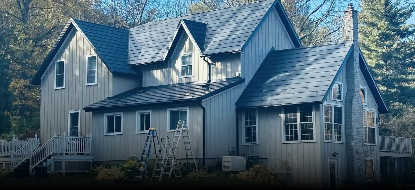 Elite Exteriors team installing new vinyl siding and seamless eavestroughs on a home in Simcoe, Ontario